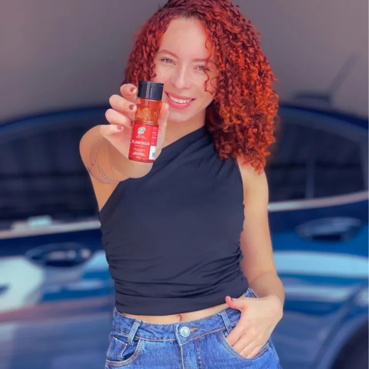 Ludy Paim, criadora de vídeos UGC, com cabelo cacheado ruivo, segurando um produto